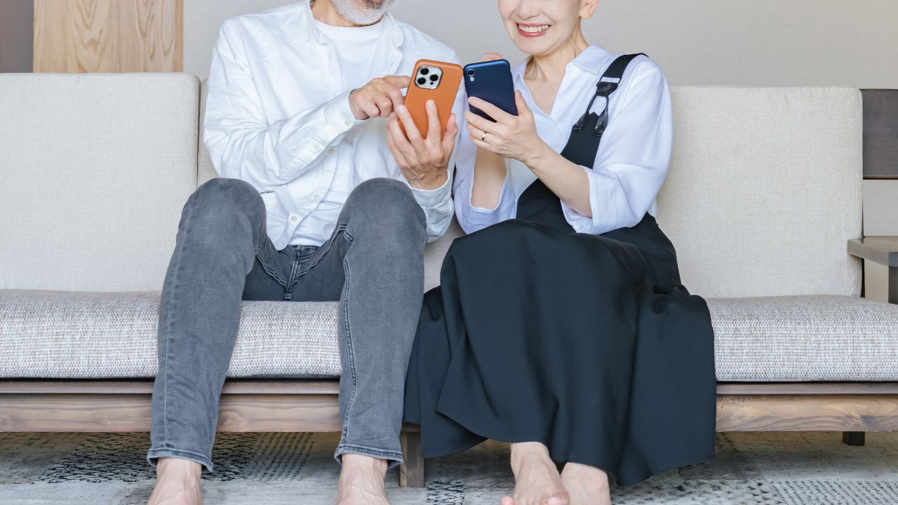 ソファでスマートフォンを見ながら話している男女の画像