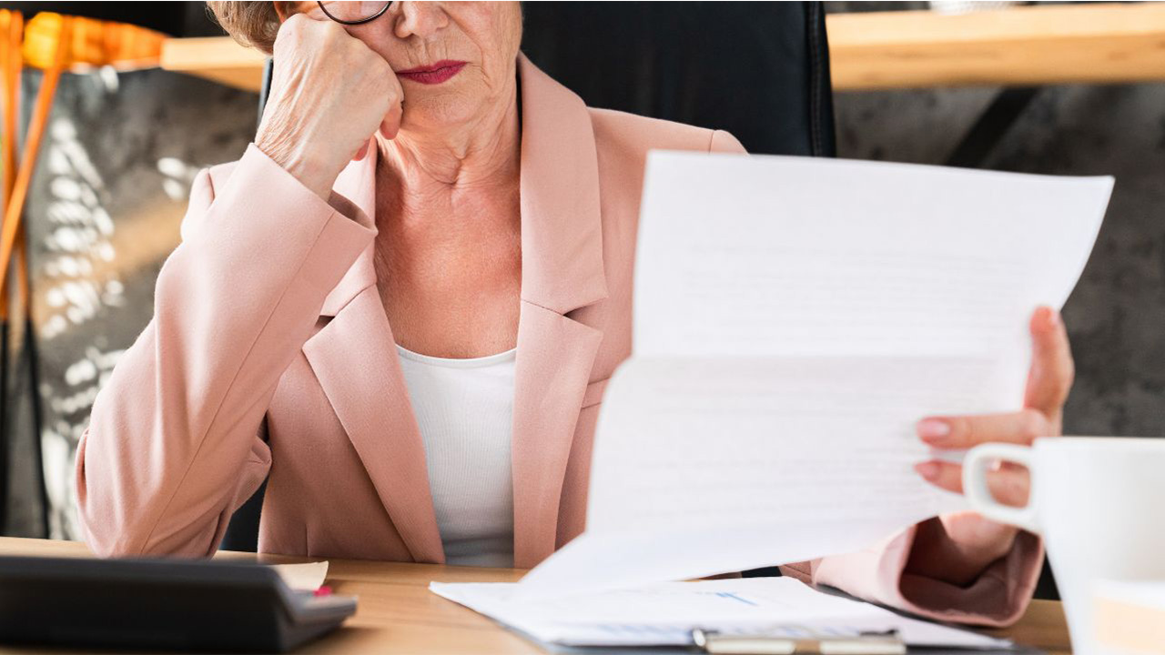 書類を読みながら考え込んでいる女性の画像