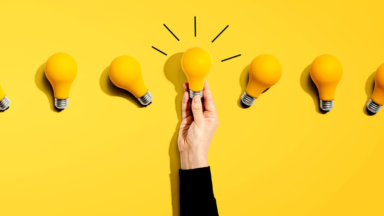 並んだ電球のうちの一つを手で掴んでいる画像