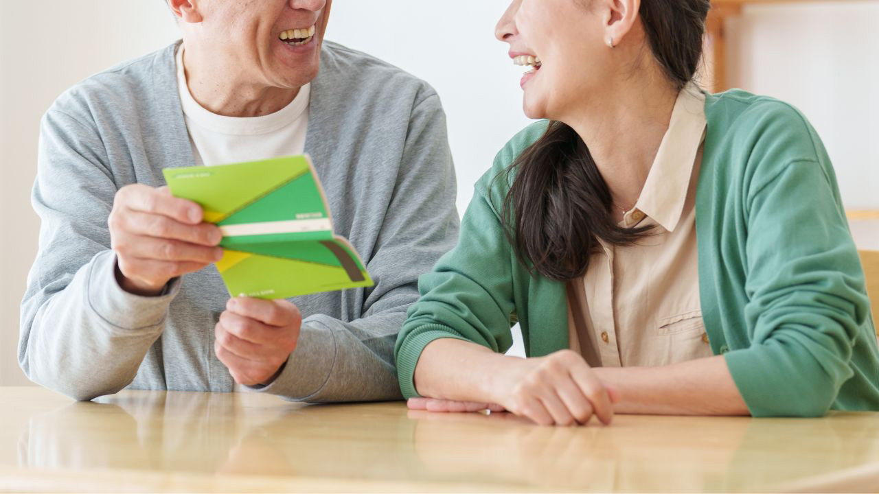 通帳を見て微笑み合う夫婦の画像