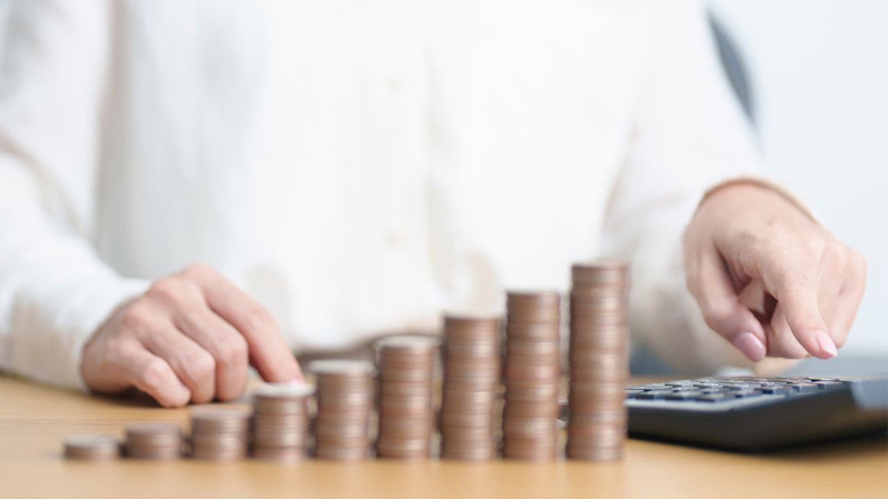 積み上げられた硬貨と、計算機で計算をする画像