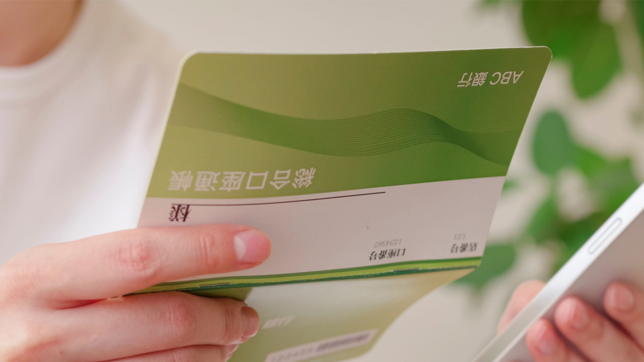 通帳を確認しスマートフォンで計算しているところ