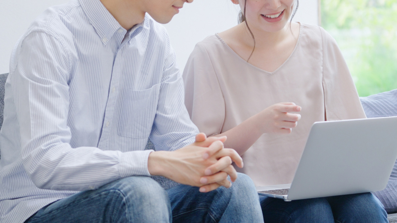 パソコンを眺める夫婦の画像