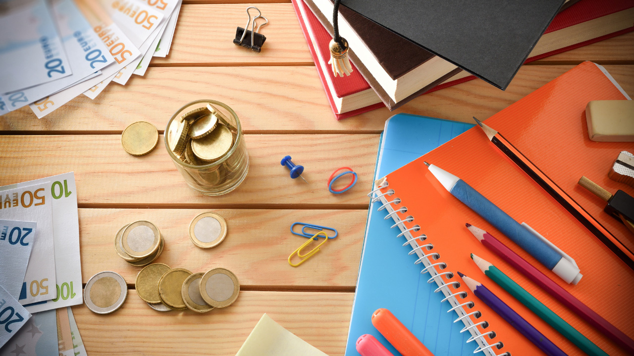 テーブルの上に散らばっている紙幣やコイン・文房具の画像