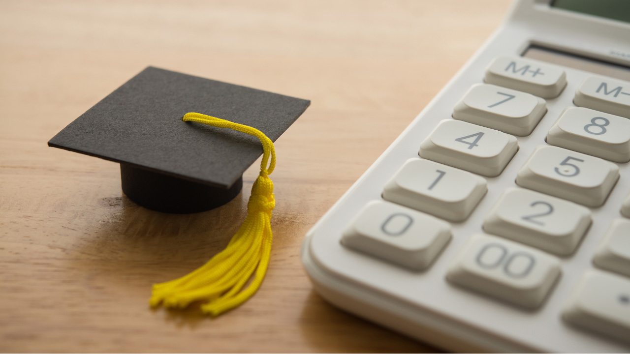 机の上に置かれた小さな卒業帽と電卓の画像