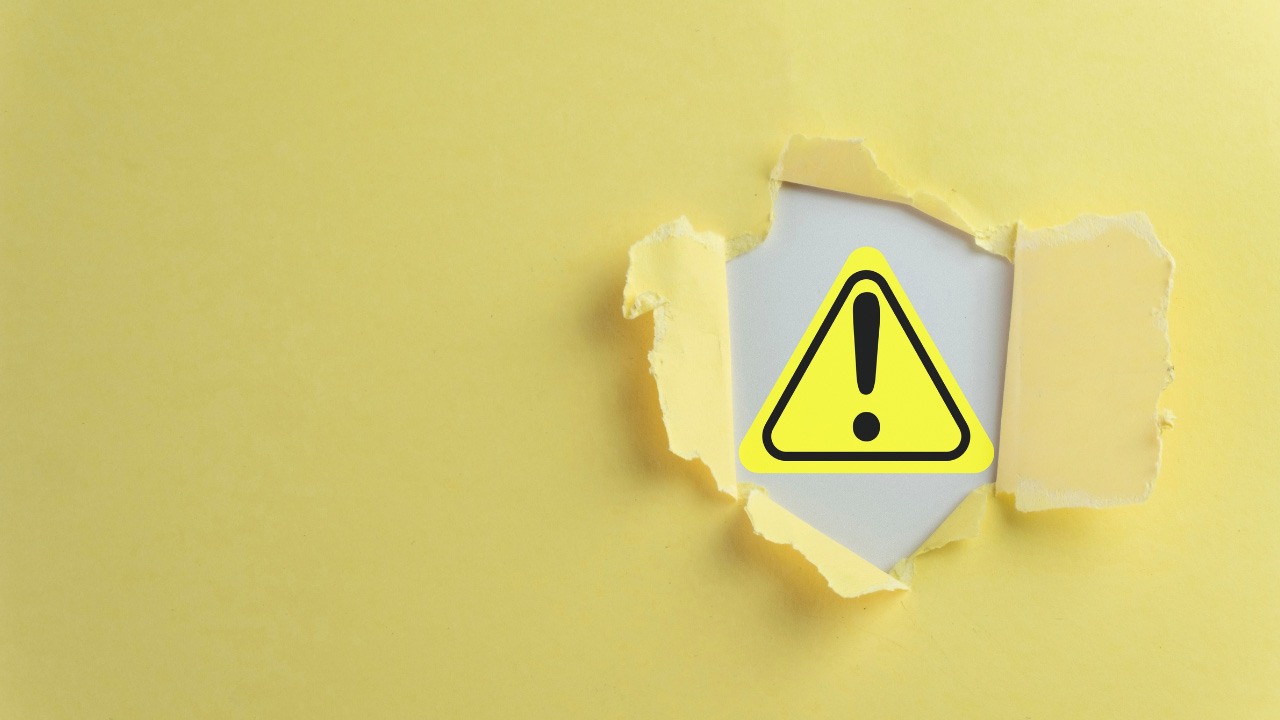 破れた紙から警告マークが見える画像