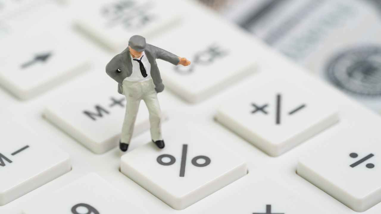 電卓の上に立つ男性フィギュアの画像