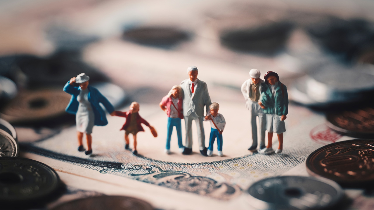 紙幣と硬貨の上に置かれた家族のフィギュアの画像