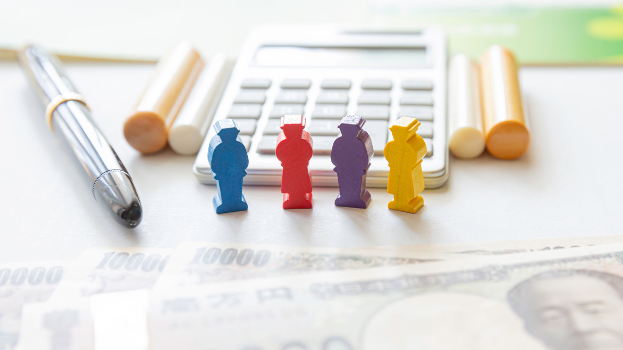 計算機、ペン、紙幣、カラフルな人型の模型が並べられた画像