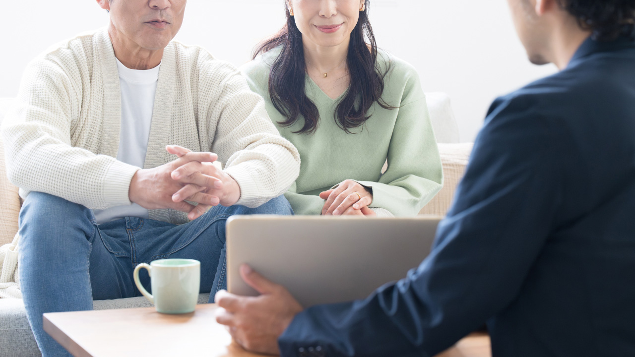 テーブル越しにノートパソコンを使用して相談している様子の画像