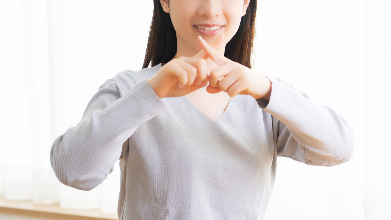 女性が指でバツを示している画像