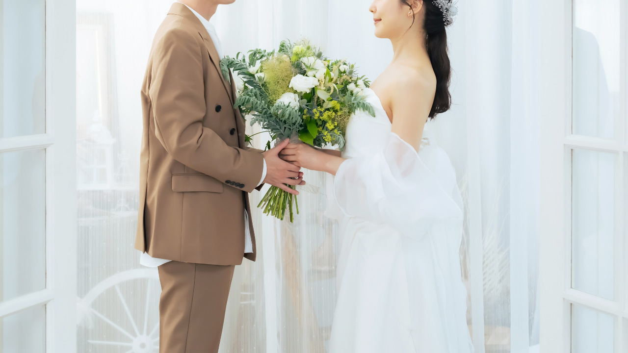 結婚式の衣装を着た男女が花束を持っている画像